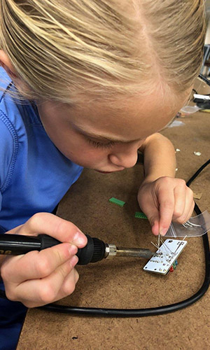 Young girl soldering a circut board