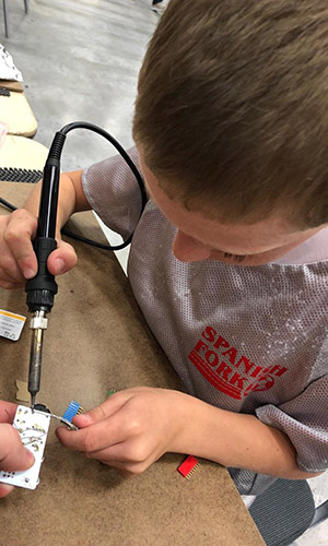 Young boy soldering a circut board